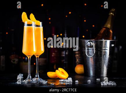 Boisson alcoolisée à l'abricot Bellini avec prosecco, cava ou vin mousseux avec purée d'abricot, sirop et glace, fond de comptoir de bar sombre, copie s Banque D'Images