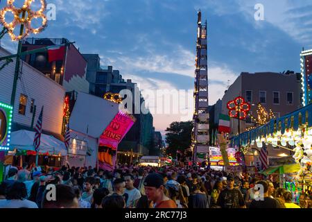 Brooklyn, NY, États-Unis. 12 juillet 2023. Un grand clocher, parsemé de lys et portant une bande, est porté sur les épaules des paroissiens et défilé à travers la paroisse dans le cadre de la fête de notre-Dame du Mont Carmel dans le quartier Williamsburg de Brooklyn. Le clocher, ou « giglio », est rebondi, ou « dansé » dans la rue plusieurs fois pendant la fête de 11 jours, y compris cet « ascenseur de nuit ». Une vue propre North 8th Street au giglo. Crédit : Ed Lefkowicz/Alamy Live News Banque D'Images