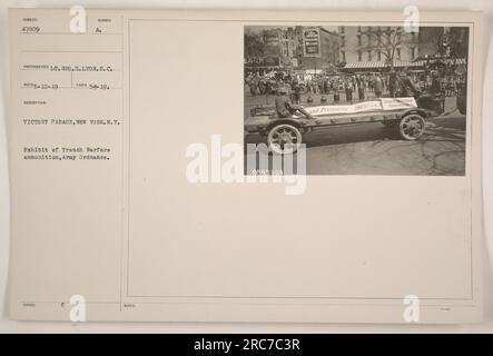 Cinquante soldats défilent dans une rue bondée de New York lors d'un défilé de la victoire en 1919. En arrière-plan, une exposition présente des munitions Trench Warfare de l'armée de terre. Cette photographie, prise par le lieutenant Geo. H. Lyon, S.C., capture un moment de célébration et la fierté des soldats victorieux. Banque D'Images