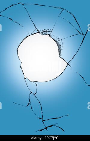 Grand trou dans le fond de fond bleu et blanc de verre de fenêtre. Verre cassé avec fissures Banque D'Images