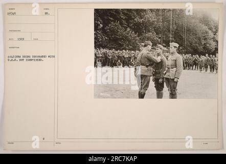La photographie, intitulée 111-SC-26746, capture une scène de 1919 pendant la première Guerre mondiale. Sur l'image, on voit des soldats décorés de la Croix du service distingué (D.S.C.), mais leur identité reste indéterminée. La photographie a été prise par un photographe nommé Reco. Des notes supplémentaires faisant référence à 26746 sont également incluses. Banque D'Images