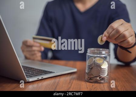 Homme mettant des pièces dans un bocal. Investissement et économie d'argent, banque et finance, achats en ligne sur Internet, comptabilité et fiscalité Business concept. Banque D'Images