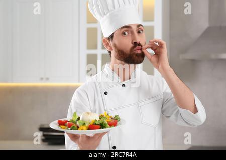 Chef professionnel présentant une délicieuse salade dans la cuisine Banque D'Images