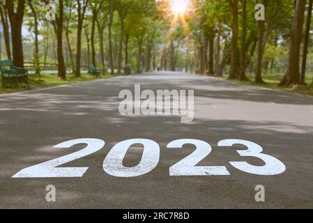 Nouvelle année 2023 ou concept simple. Texte 2023 écrit sur la route au milieu de la route asphaltée avec au coucher du soleil. Banque D'Images