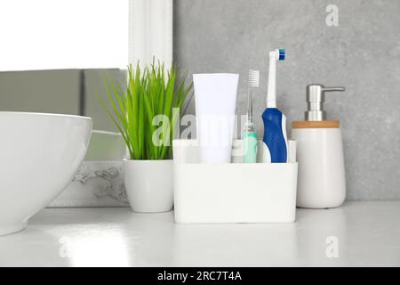 Brosses à dents électriques et tube de pâte sur comptoir blanc dans la salle de bain Banque D'Images