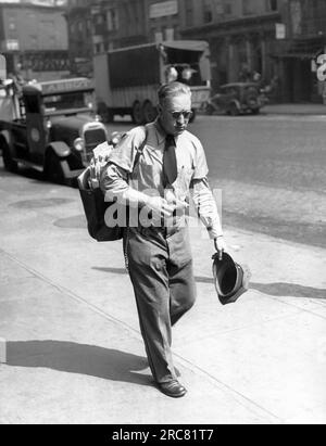 New York, New York : c. 1937 Un facteur qui semble très chaud alors qu'il livre le courrier par une chaude journée dans la ville. Banque D'Images