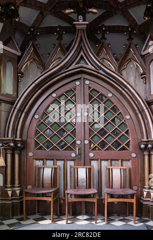 Intérieur de l'église de St. Anne dans la vieille ville de Vilnius, avec une vieille porte voûtée avec un beau cadre en bois bloqué par des chaises Banque D'Images