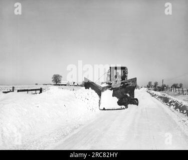 États-Unis : c. 1960 Chasse-neige défrichant les routes rurales après une tempête de neige Banque D'Images