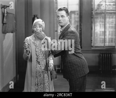 Hollywood, Californie : c. 1939 Un homme couvre la bouche d'une femme alors qu'ils regardent tous les deux dans la peur et l'étonnement. Banque D'Images