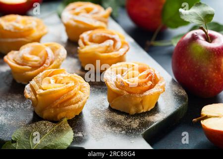 Mini-tartes Apple Rose avec sucre glace sur la planche à découper en pierre. Banque D'Images