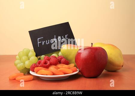 Carte avec mot fructose, délicieux fruits mûrs, framboises et abricots secs sur table en bois Banque D'Images