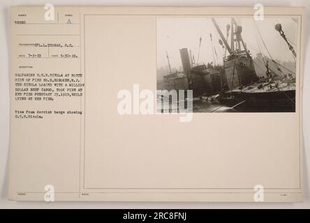 Opérations de récupération ayant lieu au quai n° 9 à Hoboken, New Jersey Les États-Unis Le Sixola, qui transportait une précieuse cargaison de bœuf d’une valeur d’un million de dollars, a pris feu le 23 février 1919. L'image représente la vue d'une barge de derrick, montrant le U.S.S. Sixola comme des efforts sont faits pour le sauver. Cette photographie a été prise par le CPL Thomas, S.C. le 30 mai 1919. Banque D'Images