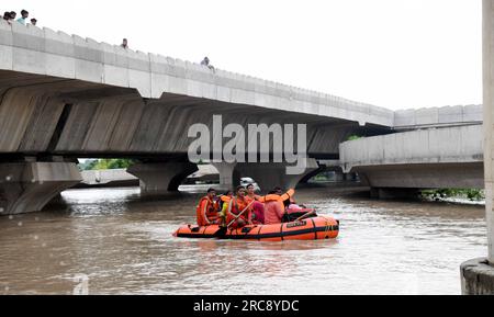 New Delhi, Inde. 12 juillet 2023. Les membres de la National Disaster Response Force (NDRF) aident les gens à évacuer les zones de basse altitude après que la rivière Yamuna ait gonflé en raison de pluies incessantes dans l’est de Delhi, en Inde, le 12 juillet 2023. Crédit : Str/Xinhua/Alamy Live News Banque D'Images