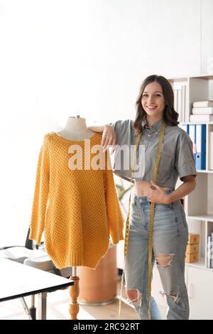 Créateur de mode féminin conçoivent une nouvelle collection de vêtements à la mode. jeune belle femme tailleur se penchant sur le porte-vêtements Banque D'Images