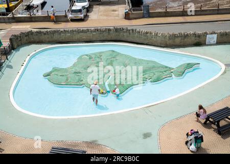 Une famille joue dans une pataugeoire en forme de l'île de Wight à Ventnor, île de Wight. Banque D'Images