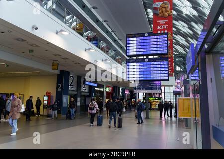 Poznan, Pologne - 19 avril 2023 : gare routière et ferroviaire, tableau de bord électronique moderne avec horaires de transport, passagers. Banque D'Images