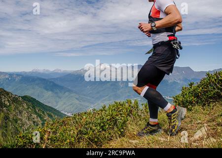 athlète masculin courant à flanc de montagne dans des manches de compression sur ses pieds dans la course de marathon de montagne Banque D'Images