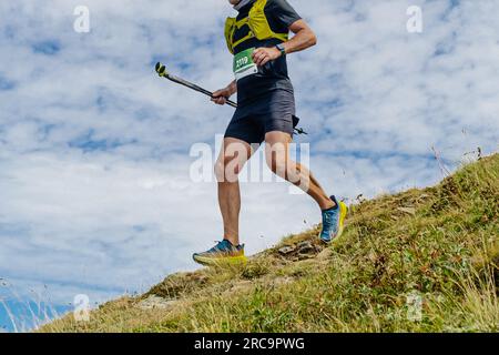 athlète masculin courir à flanc de montagne avec des bâtons de trekking de sentier à la main, course de marathon de montagne Banque D'Images