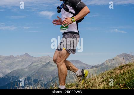 athlète féminine courant à flanc de montagne en leggings, course de marathon de montagne, ciel de fond Banque D'Images