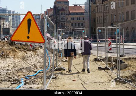 Poznan, Pologne - 21 avril 2023 : clôture et marquage avec un panneau d'avertissement d'une zone dangereuse de réparation des communications et d'une route sur une rue de la ville. Banque D'Images