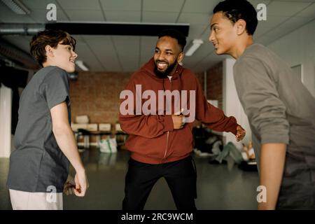 Professeur de danse masculin souriant enseignant à des élèves adolescents en studio au lycée Banque D'Images