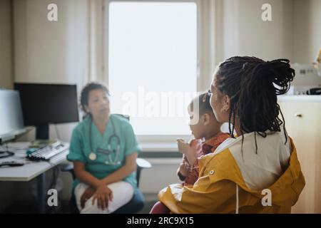 Femme avec fille visitant la femme pédiatrique en clinique Banque D'Images