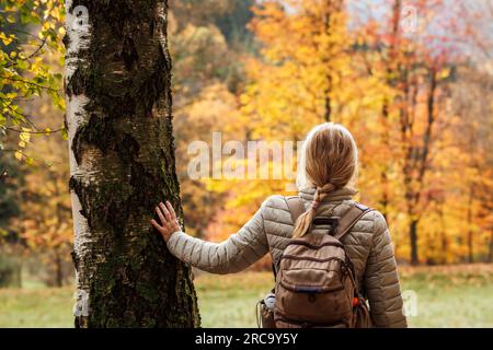 Femme avec sac à dos profitant de la vue sur la forêt d'automne pendant la randonnée dans la nature. Activités de loisirs et détente en plein air Banque D'Images