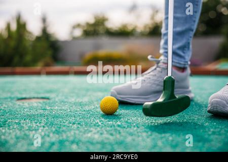 Golfeur jouant au golf miniature et essayant de mettre la balle dans le trou. Activité de loisirs en été Banque D'Images