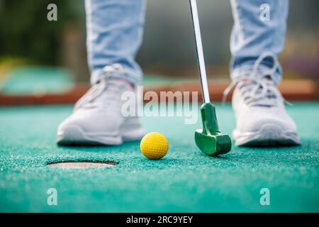 Golfeur jouant aventure ou mini golf et essayant de mettre la balle dans le trou. Activité sportive estivale Banque D'Images