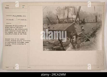 Sauvetage des U.S.S. Sixola at Pier No. 9, Hoboken, N.J. Le Sixola, transportant des marchandises précieuses pour la France, prit feu le 23 février 1919, alors qu'il était amarré à la jetée. Cette photographie montre le Sixola coulé et les activités entourant la construction d'un cofferdam, avec des pompes et des plongeurs se préparant à submerger. [Photographe : CPL.L. THOMAS, S.C.] Banque D'Images