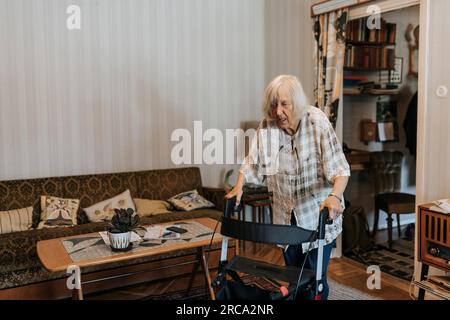Femme âgée utilisant la marchette de mobilité tout en marchant à la maison Banque D'Images