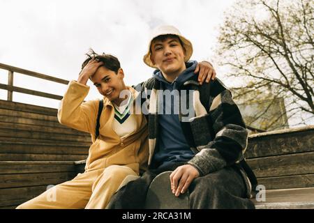 Portrait d'amis masculins souriants assis ensemble sur des marches Banque D'Images