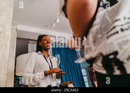 Vue à angle bas de femme d'affaires souriante tenant un verre à boisson pendant l'événement au centre des congrès Banque D'Images