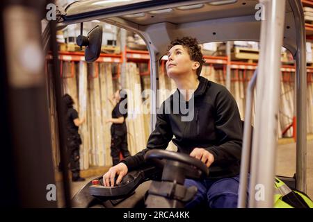 Femme opérateur de chariot élévateur travaillant dans l'industrie du bois Banque D'Images