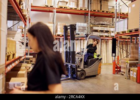 Femme opérateur de chariot élévateur regardant vers le haut tout en travaillant dans l'industrie du bois Banque D'Images