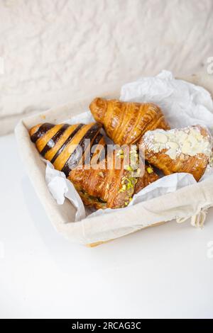 quatre types de croissants dans un panier sur une table blanche Banque D'Images