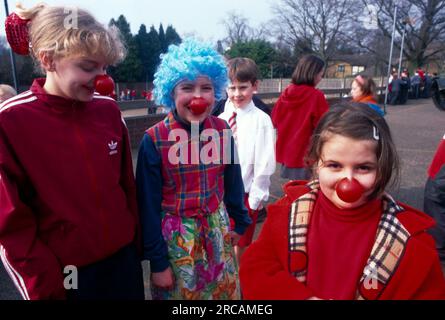 Enfants portant le nez rouge pour Comic relief enfant habillé en Clown dans le terrain de jeu de l'école Banque D'Images
