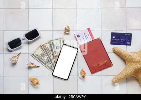 Composition avec téléphone portable, argent, carte de crédit et coquillages sur fond de tuile clair Banque D'Images