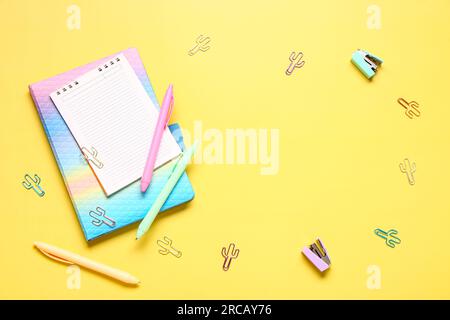 Cadre fait de papeterie scolaire différente et cahier vierge sur fond jaune Banque D'Images