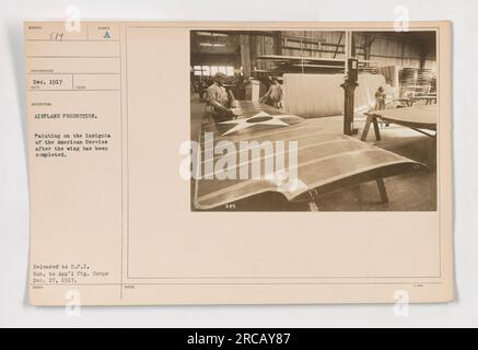 Des ouvriers peignent les insignes du Service américain sur une aile d'avion. La photographie a été prise en décembre 1917 pendant la production de l'avion. La photographie porte le numéro 111-SC-589 et a été remise à l'ICP (Comité sur l'information publique) et le Appalachian signal corps le 27 décembre 1917. Banque D'Images