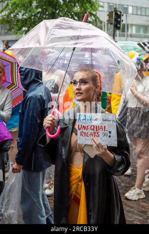 La pluie ne nous dérange pas, les droits inégaux le font ! Jeune femme tenant une pancarte faite à la main et un parapluie transparent au défilé de la Pride 2023 d'Helsinki. Banque D'Images