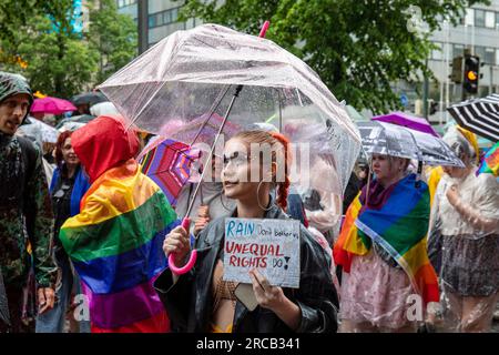 Jeune femme avec parapluie transparent et signe fait main à Helsinki Pride 2023 défilé un jour de pluie à Helsinki, Finlande Banque D'Images