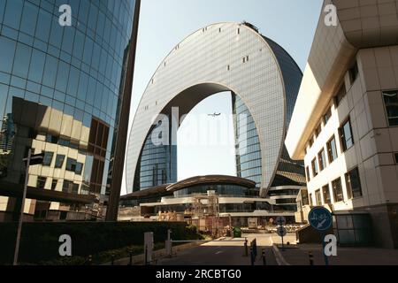 Bakou, Azerbaïdjan - 26 juin 2023 : vue rapprochée du matin de l'hôtel Crescent, avec un avion passant par la brèche au milieu de la structure Banque D'Images