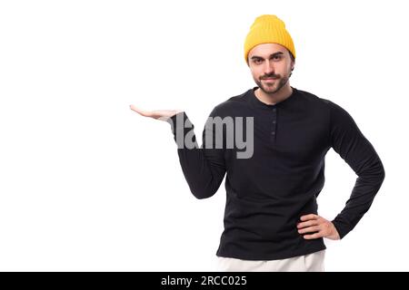 Jeune brune européen brutal homme dans un sweat-shirt noir montre sa main au mur Banque D'Images