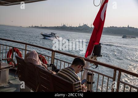 Istanbul, Turquie. 13 juillet 2023. Certains passagers dans la zone ouverte du ferry ont vu se couvrir le visage du soleil pendant le temps chaud à Istanbul. (Photo Onur Dogman/SOPA Images/Sipa USA) crédit : SIPA USA/Alamy Live News Banque D'Images