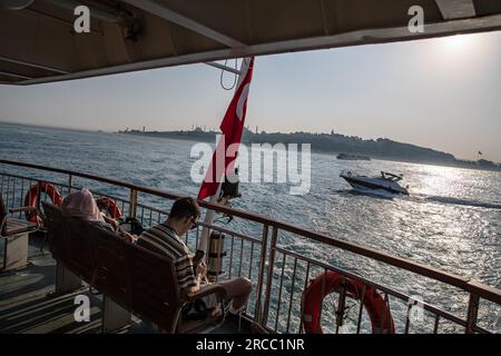 Istanbul, Turquie. 13 juillet 2023. Certains passagers dans la zone ouverte du ferry ont vu se couvrir le visage du soleil pendant le temps chaud à Istanbul. (Photo Onur Dogman/SOPA Images/Sipa USA) crédit : SIPA USA/Alamy Live News Banque D'Images