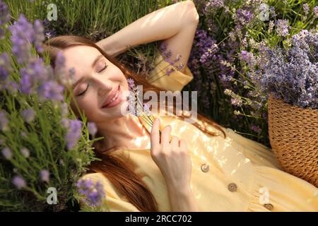 Jeune femme couché dans le champ de lavande le jour d'été Banque D'Images