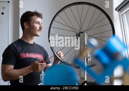 13 juillet 2023, Saxe, Chemnitz : Erik Fickelscheer fabrique une roue à rayons textiles à la manufacture Pi Rope de Chemnitz. Au lieu de l'acier, la manufacture de rayons et de roues fabrique des rayons en Vectran, un polyester à haute résistance. Cela rend les roues des vélos particulièrement légères. L'industrie de la bicyclette en Saxe a bénéficié de l'essor du secteur ces dernières années et ouvre la voie à l'avenir. Par exemple, de nouvelles start-ups ont vu le jour aux côtés de la société traditionnelle Diamant. Avec environ 10 000 employés dans plus de 300 entreprises, l'industrie en Saxe génère des ventes annuelles de Banque D'Images