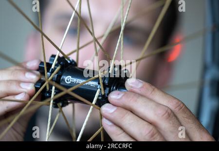 13 juillet 2023, Saxe, Chemnitz : David Wegehaupt vérifie une roue à rayons textiles en production à la manufacture Pi Rope. Au lieu de l'acier, la manufacture de rayons et de roues fabrique des rayons en Vectran, un polyester à haute résistance. Cela rend les roues des vélos particulièrement légères. L'industrie de la bicyclette en Saxe a bénéficié de l'essor du secteur ces dernières années et ouvre la voie à l'avenir. Par exemple, de nouvelles start-ups ont vu le jour aux côtés de la société traditionnelle Diamant. Avec environ 10 000 employés dans plus de 300 entreprises, l'industrie en Saxe génère des ventes annuelles o Banque D'Images