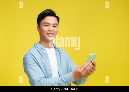 Le gars asiatique excité tenant smartphone se sent surpris de parier gagner sur téléphone portable, célébrant le succès Banque D'Images